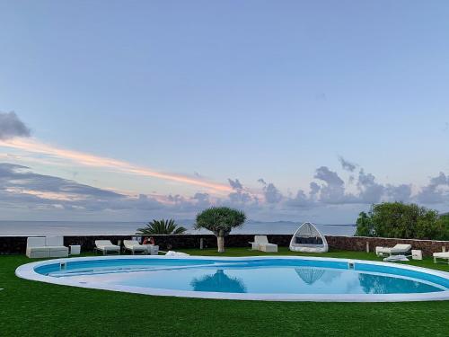 a swimming pool in the middle of a lawn with chairs at VillaMare in Puerto del Carmen