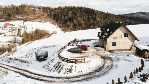 a house with two cars parked in the snow at Chata Kukuryku in Baligród