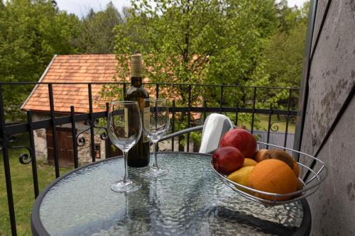 una mesa de cristal con un bol de fruta y dos copas de vino en Apartman Tinče en Delnice