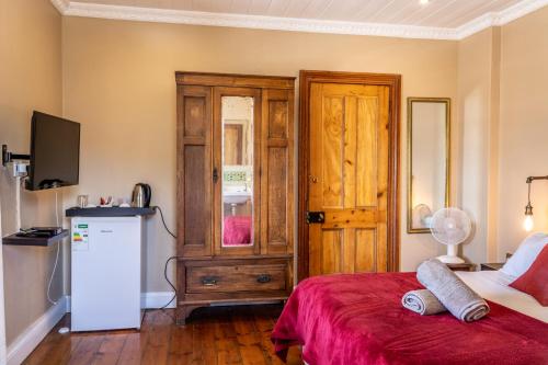 a room with a bed and a refrigerator and a door at Sandstone Manor in Mossel Bay
