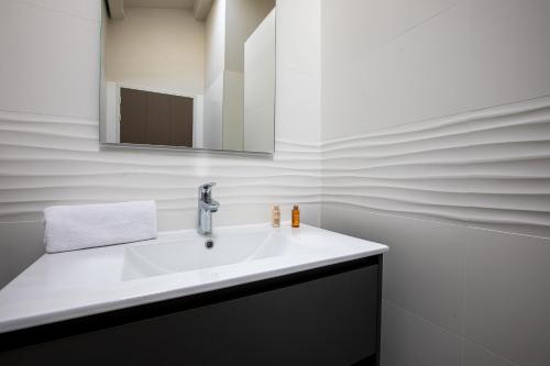 Un baño con un lavabo blanco y un espejo. en Appartement lumineux pour 6 personnes, en Le Bois-Plage-en-Ré