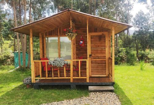 un cobertizo de madera con una mesa en el césped en Casa de leña, cabaña rural, en Villa de Leyva