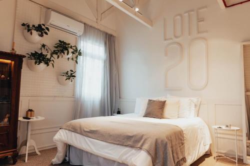 a white bedroom with a bed and a window at LOTE20 Hotel Boutique in Bento Gonçalves