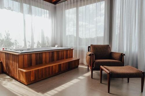 a bathroom with a tub and a chair and a window at LOTE20 Hotel Boutique in Bento Gonçalves