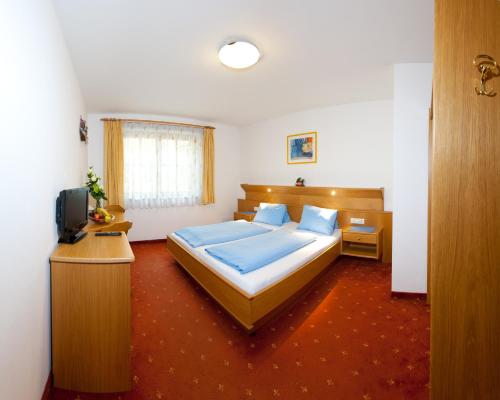 a bedroom with a large bed and a television at der Steinerwirt in Wagrain