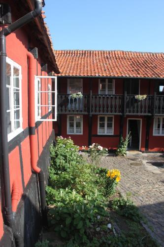 a red building with a balcony and flowers at Pension Sandbogaard in Sandvig