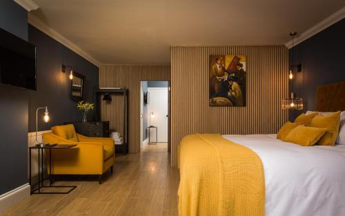 a hotel room with a bed and a yellow chair at Willowbeck Lodge Boutique Hotel in Carlisle