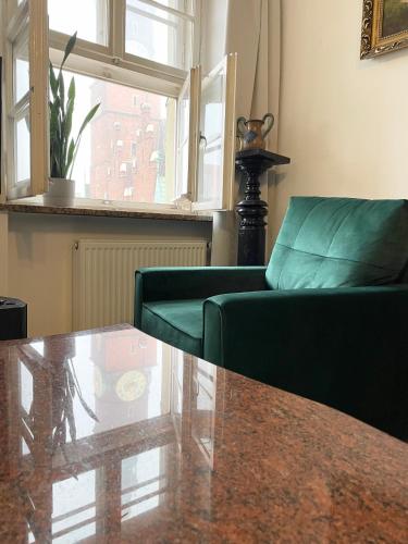 a living room with a glass table and green chairs at Wroclaw Inn Apartments in Wrocław