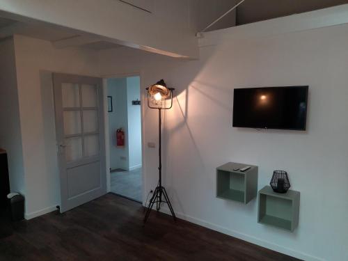 a room with a light on a white wall with a television at B&B D'n Optie in Druten