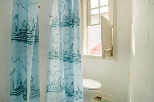 uma casa de banho com um WC e uma cortina de chuveiro azul em Casa Espaçosa Ilha de Paquetá no Rio de Janeiro