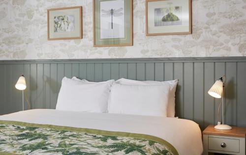 a bedroom with a bed with white pillows and two lamps at Governors House by Greene King Inns in Cheadle Hulme