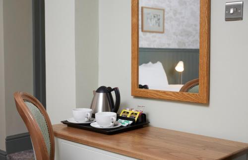 a table with a tray with cups and a mirror at Governors House by Greene King Inns in Cheadle Hulme