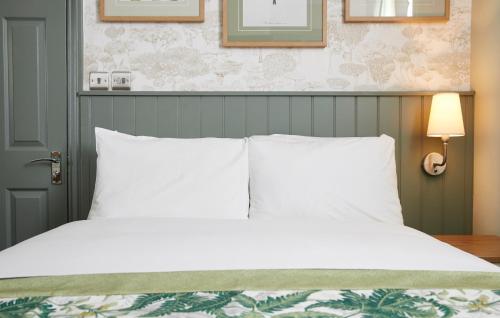 a bed with white sheets and pillows in a bedroom at Governors House by Greene King Inns in Cheadle Hulme