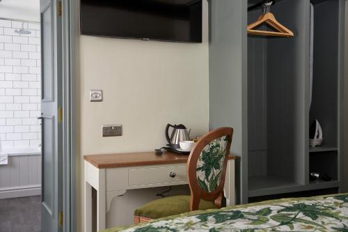 a bedroom with a desk with a chair next to a bed at Governors House by Greene King Inns in Cheadle Hulme