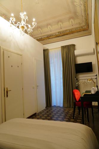a bedroom with a bed and a desk and a chandelier at DS Apartment in Catania