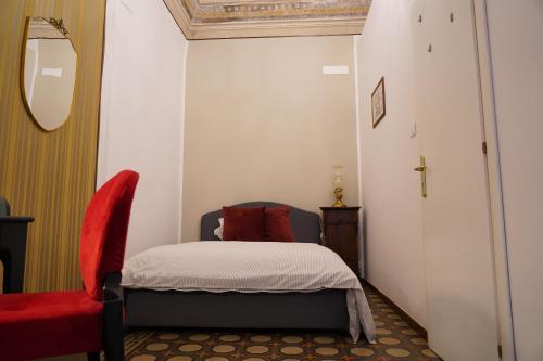 a small bedroom with a bed and a red chair at DS Apartment in Catania