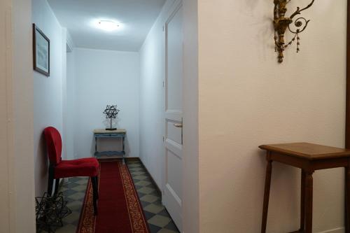 a hallway with a red chair and a table at DS Apartment in Catania