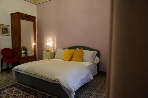 a bedroom with a bed with yellow pillows and a mirror at DS Apartment in Catania
