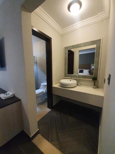 a bathroom with a sink and a mirror and a toilet at L'Aurora Inn in Guatemala