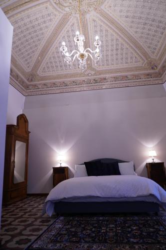 a bedroom with a ceiling with a bed and a chandelier at DS Apartment in Catania