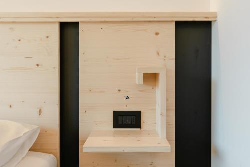 a bedroom with a wooden wall with a clock on it at Garnì Aurora Bed and Breakfast in Soraga