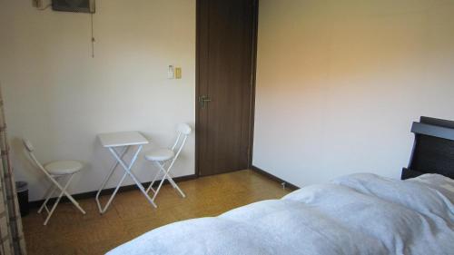 a bedroom with two chairs and a table and a bed at Ken House Osaka in Takatuki