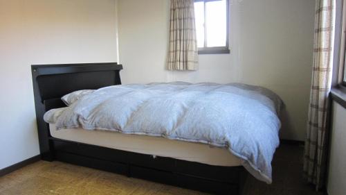 a bed with a blue comforter in a bedroom at Ken House Osaka in Takatuki