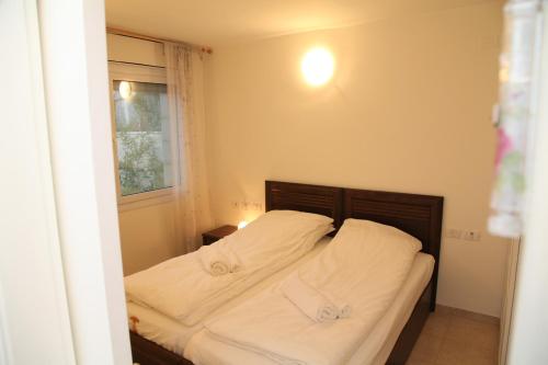 a bedroom with a bed with white sheets and a window at Apartment Tal in the Judean Desert in Kfar Adumim