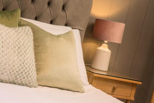 a bed with a pillow and a lamp on a night stand at Willowbeck Lodge Boutique Hotel in Carlisle