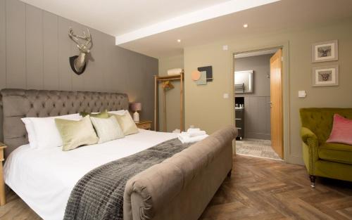 a bedroom with a large bed and a green chair at Willowbeck Lodge Boutique Hotel in Carlisle
