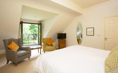 a bedroom with a bed and two chairs and a window at Willowbeck Lodge Boutique Hotel in Carlisle