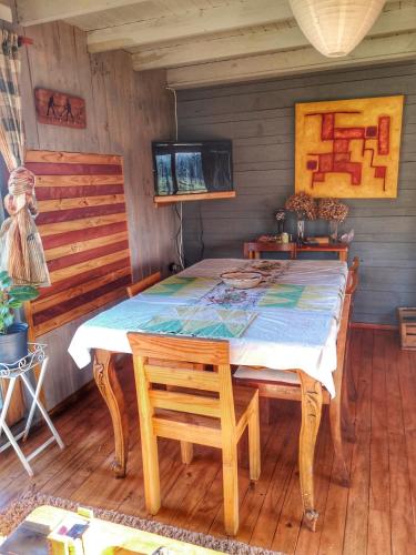 a dining room with a wooden table and chairs at Ecolodge Lanalhue Hostel in Cañete