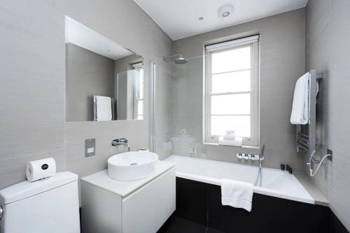 biała łazienka z umywalką i wanną w obiekcie Recently redecorated bright 1BR near Shepherds Bush with parking SOA w Londynie