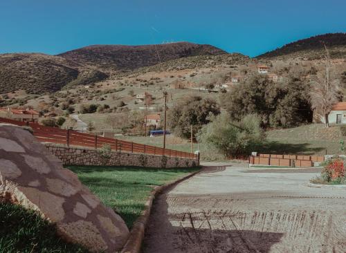 un camino con una valla al lado de una montaña en Mezonetes Helmos en Áno Lousoí