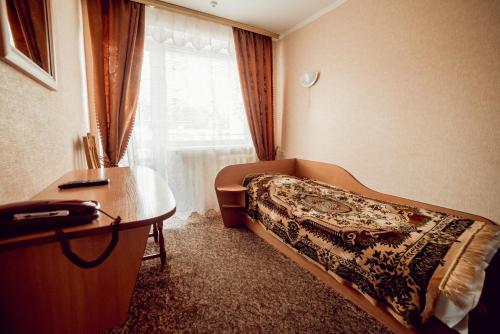 a bedroom with a bed and a desk and a window at ПОДІЛЛЯ in Vinnytsya