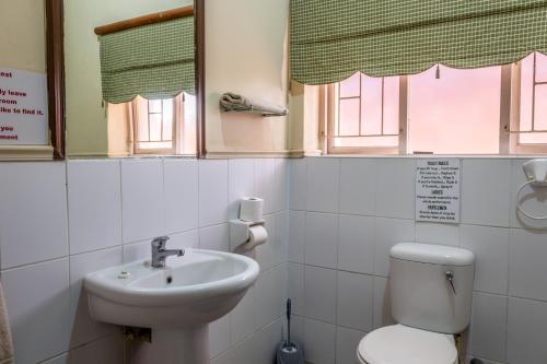 a bathroom with a sink and a toilet and windows at Bay Vista Guesthouse in Mossel Bay