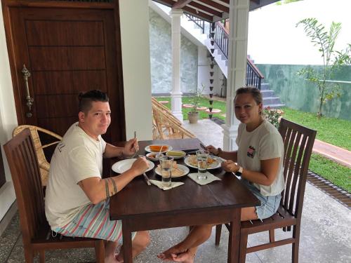two men sitting at a wooden table eating food at Summer Time Hiriketiya in Dickwella