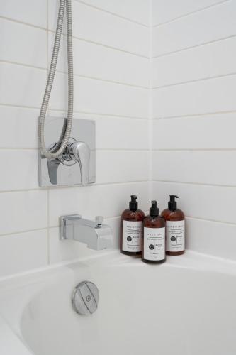a bathroom sink with three bottles on a shelf at Hotel-Apart Prince Arthur in Montreal