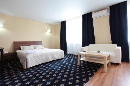 um quarto de hotel com uma cama e um sofá em Troya Hotel em Rudny