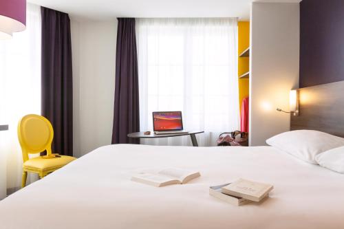 a hotel room with a bed with a book and a laptop at ibis Styles Saumur Gare Centre in Saumur