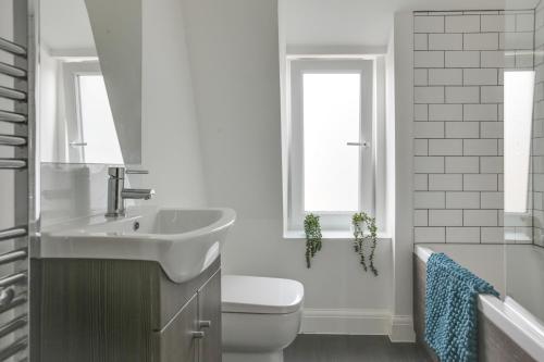 a white bathroom with a sink and a toilet at Beautiful Chelmsford Apartment in Chelmsford