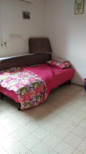 1 dormitorio con 1 cama con colcha rosa en Private room near the Airport for amazing people, en Lod