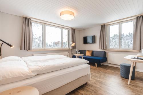 a bedroom with a large bed and a blue chair at Hotel Alpensonne - Panoramazimmer & Restaurant in Arosa