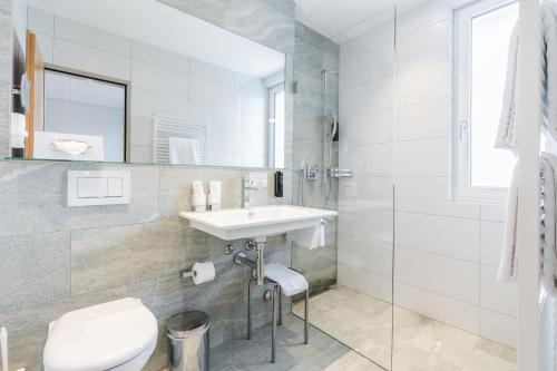 a white bathroom with a sink and a toilet at Hotel Alpensonne - Panoramazimmer & Restaurant in Arosa