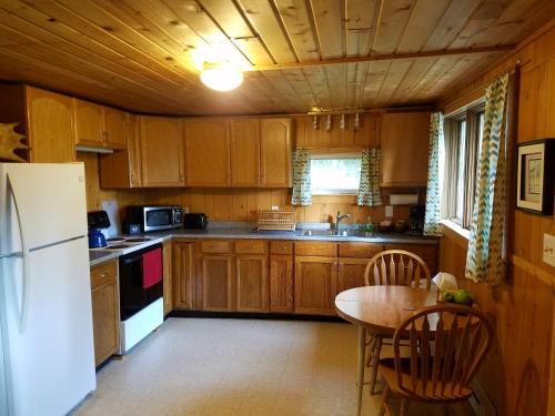 a kitchen with wooden cabinets and a table and a refrigerator at Northwoods Cottage Bed and Breakfast in Fairbanks