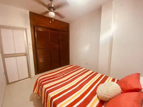 a bedroom with a bed with a striped blanket and a window at Mayo apartamentos in Santiago