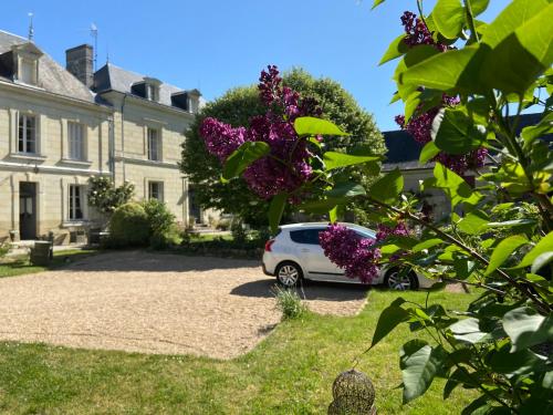 un coche aparcado frente a una casa con flores púrpuras en La Pénesais, en Beaumont-en-Véron