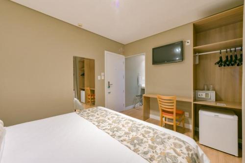 a bedroom with a bed and a desk and a tv at Araçatuba Plaza Hotel in Araçatuba