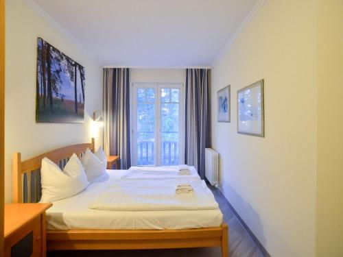 una camera d'albergo con letto e finestra di Dünenpark Binz - Komfort Ferienwohnung mit 1 Schlafzimmer und Balkon im Dachgeschoss 282 a Binz