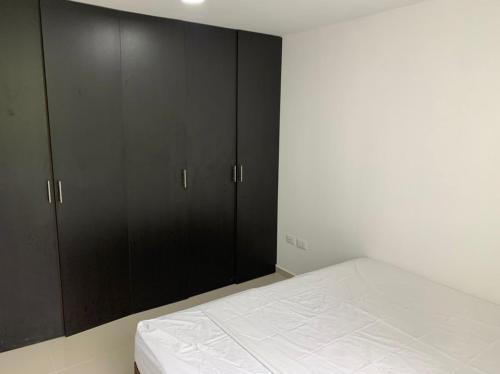 sypialnia z czarnymi szafkami i białym łóżkiem w obiekcie apartamento fortezza ByB w mieście Ibagué